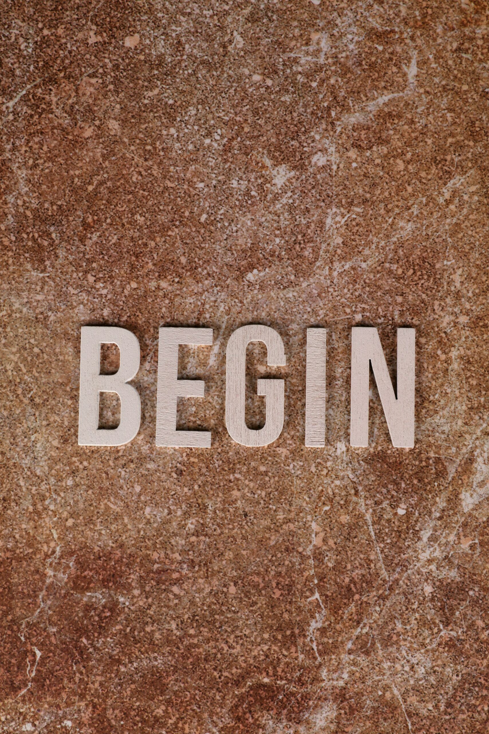 Inspirational 'Begin' text on brown marble surface, symbolizing fresh starts.